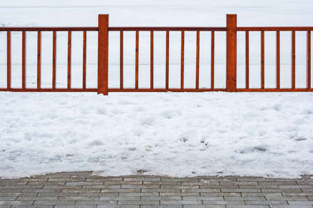 Wooden fence by the lake in the city park at winter time.の写真素材