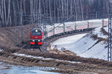 Moscow, Russia - April 03, 2021: Passenger train moves along the forest.のeditorial素材