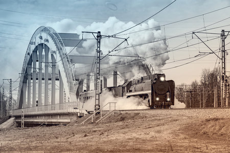 Steam retro train moves on the bridge from the station.の写真素材