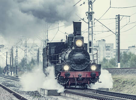 Retro steam locomotive moves under the pouring rain. Moscow.