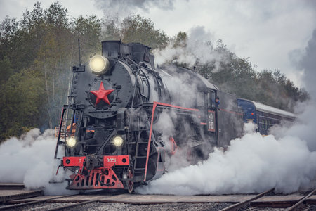 Ruskeala, Russia - October 01, 2021: Retro steam train arrives to the station wooden platform from Sortavala at cloudy autumn day.のeditorial素材