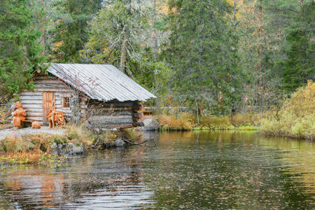 Ruskeala, Russia - October 01, 2021: Wooden house by the lake near the waterfall in Ruskeala mountain park.のeditorial素材