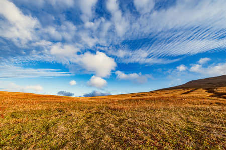 Clouds above the mountain meadow at autumn sunset.の写真素材