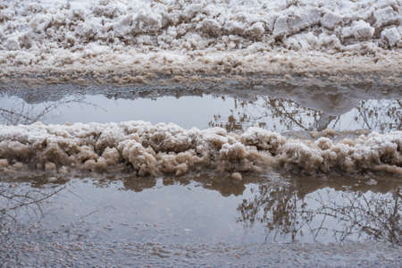 Melting snow and puddles on the road at early spring.