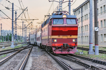 Passenger retro electric czech locomotive with train departs from the station at sunset time.の写真素材