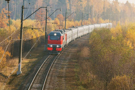 Passenger train moves at autumn foggy sunrise time.の写真素材