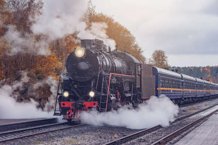 Retro steam train departs from the station wooden platform.の写真素材
