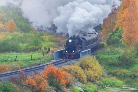 Retro steam train at autumn cloudy morning.の写真素材