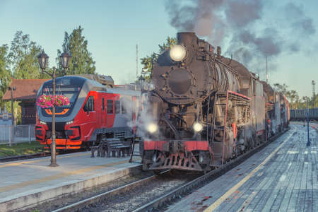 Steam locomotives stand by the wooden station platform.の写真素材