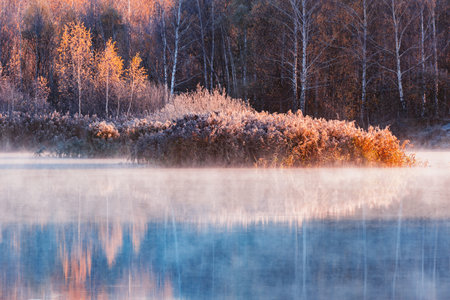 Fog above the lake surface at autumn morning time.の写真素材