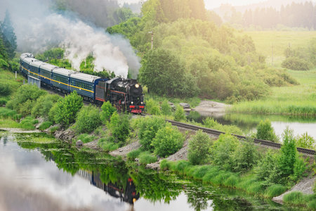 Retro steam train moves along the lake at sunrise.の写真素材
