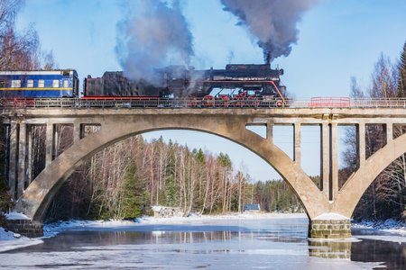 Retro steam train moves above the river.の写真素材