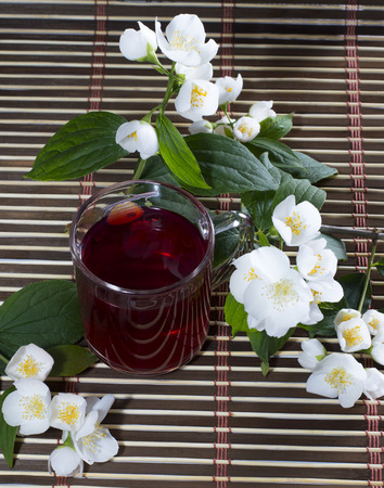 glass of the red tea decorated with flower branchesの写真素材