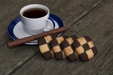 cup of coffee and cookies in a row on an old tableの写真素材