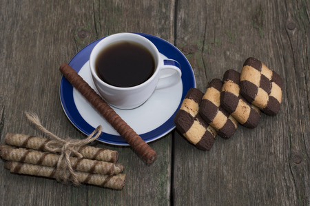 cup of black coffee and two rows of cookies on the shabby desktopの写真素材