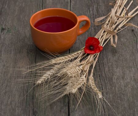 big orange mug of juice and stalks of wheatの写真素材