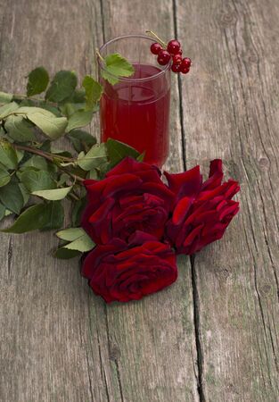 glass of juice, currant on a glass and a bouquet of red rosesの写真素材
