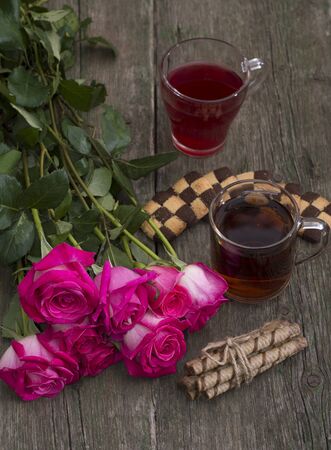 two glasses of drink, cookies and bouquet of scarlet red rosesの写真素材