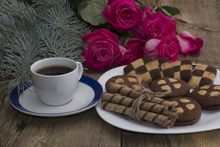 cup of coffee, roses and plate with different cookies on a tableの写真素材