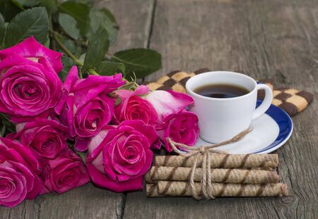 cup of coffee, cookies and bouquet of scarlet red rosesの写真素材