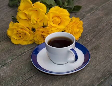 cup of coffee and yellow flowers on an old tableの写真素材