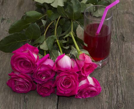 bouquet of red roses and glass of juice with a tubuleの写真素材
