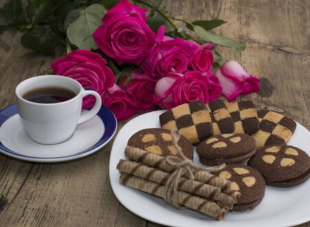 coffee and plate with cookies against red roses, a subject drinks and flowersの写真素材