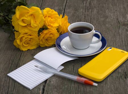 bouquet of yellow roses, phone, notebook and coffee, still life, festive cardの写真素材