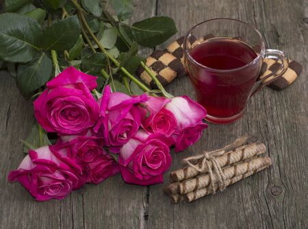 still life bouquet of roses, circle of red drink and two groups of cookies, subject beautiful flowers and drinks, greeting cardの写真素材