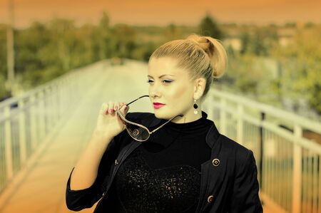 portrait of the beautiful woman on the railway bridge, a scene over the railroad, the image in a yellow key, a subject fashionable women in unusual placesの写真素材