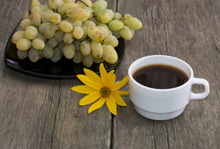 plate with grapes, a cup of coffee and a yellow flower, a still life on an old table, a subject fruit and drinksの写真素材
