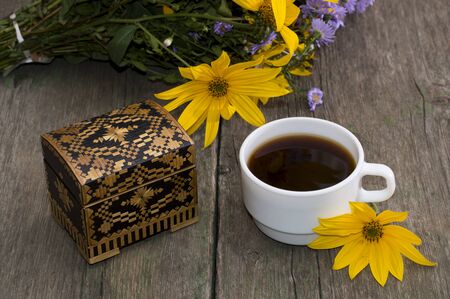 cup of coffee, wild flowers, casket and yellow flower, still life, on a wooden table, a subject flowers and drinksの写真素材