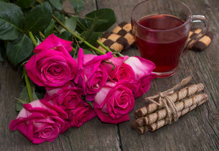 bouquet of red roses, cookies and coffee, on a wooden table, a still life, a subject flowers and drinksの写真素材