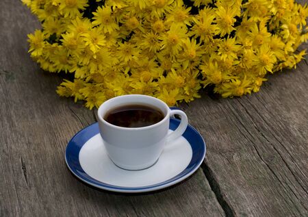 bouquet of beautiful yellow flowers and cup of black coffee, still life on a subject flowers, drinks and fallの写真素材