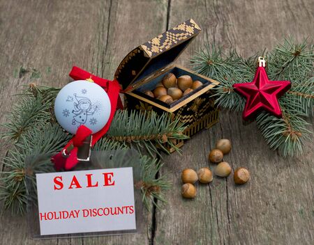 fir-tree branch with an ornament, a casket with nutlets and a label Festive Sale, on a wooden table, a subject holidays Christmas and New Yearの写真素材