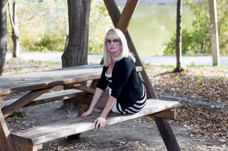 the beautiful blonde on a bench in park at the lake, a subject beautiful women and the natureの写真素材