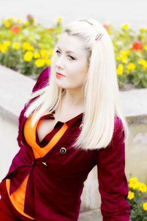 the bright beautiful blonde in a red suit at a flower bed, a subject beautiful womenの写真素材