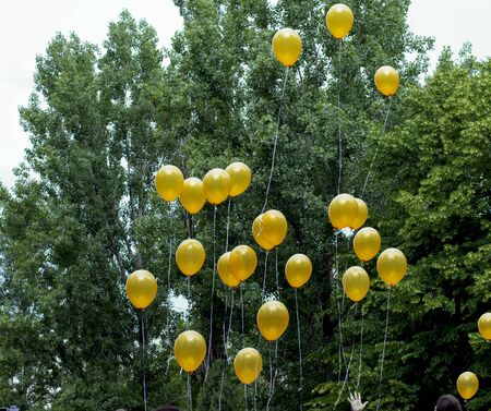 the hand releasing yellow balloons into the sky, a subject holidays, salutesの写真素材