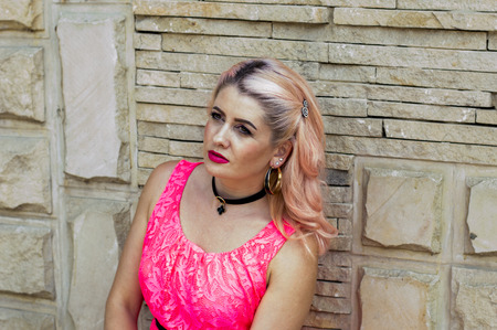 portrait of woman in pink dress by the wall, theme beautiful bright women in summerの写真素材