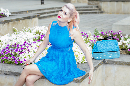 beautiful woman in blue in the flower beds with petunias, the theme of beautiful vibrant womenの写真素材