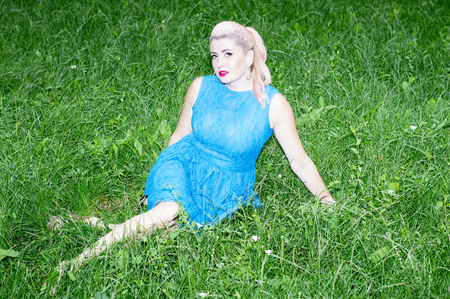 portrait of the blonde in the blue dress on the lawn, the theme of beautiful vibrant womenの写真素材