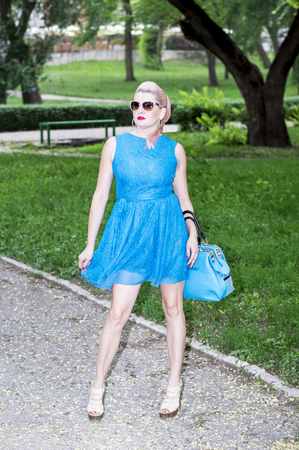 woman in blue with a handbag in the Park, the theme of beautiful vibrant womenの写真素材