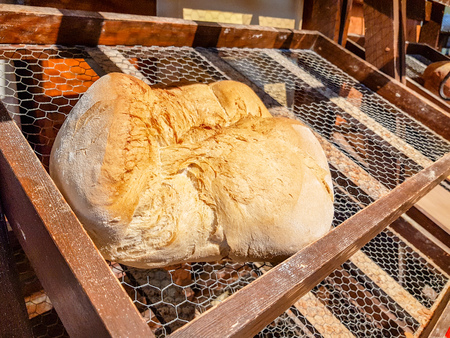 Large loaf of bread on the wooden counter and metal chess in antique bakeryの写真素材