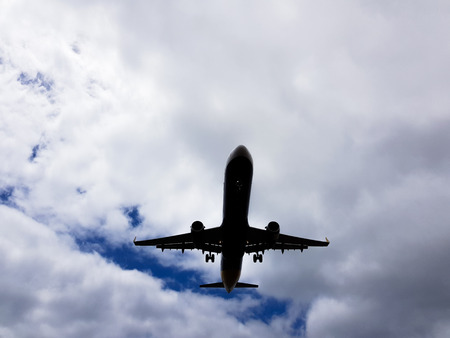 Airplane belly before landing on a blue sky background