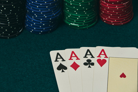 on the green table, a set of four aces is highlighted, at the bottom of the image with poker chips...