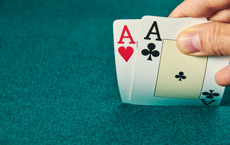 close-up of two aces held in one hand on the green game mat on the right side of the image to leave room for editing.の写真素材