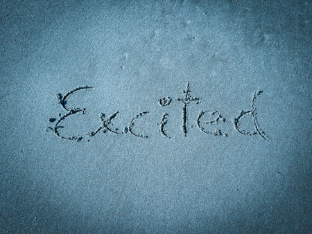 Excited, word written on blue sandの写真素材