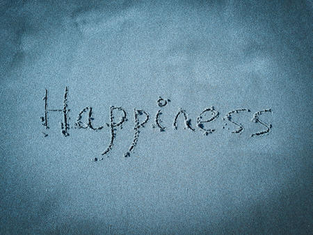 Happiness, word written on blue sandの写真素材