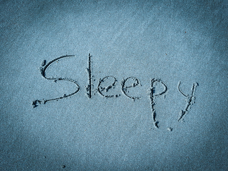 Sleepy, word written on blue sandの写真素材