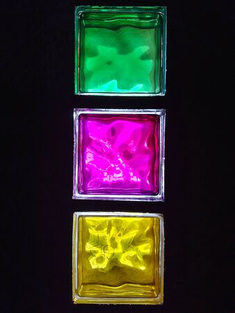 Translucent bricks that let light pass through with pink and yellow-green colours on a dark...